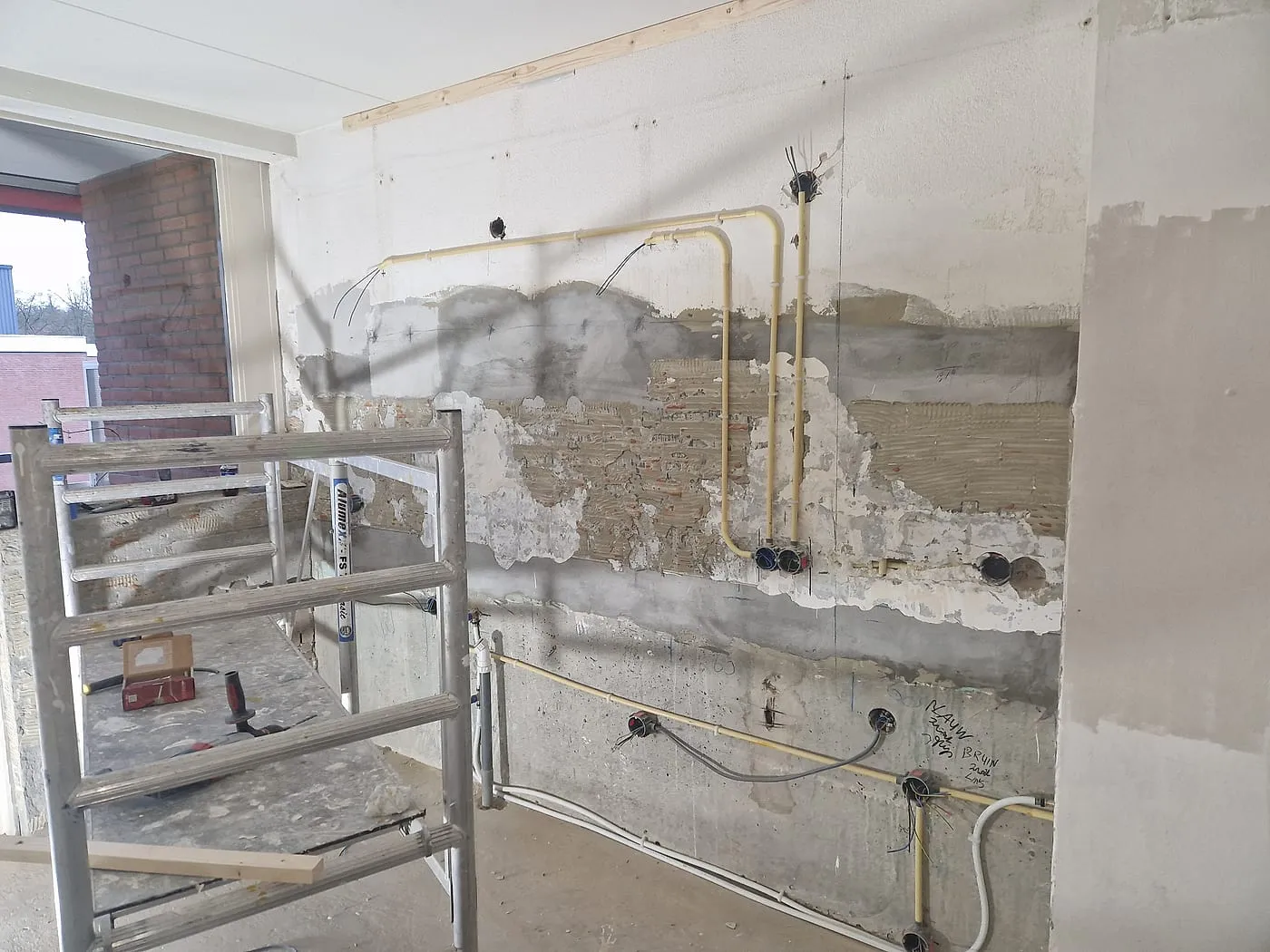 Gestripte keukenwand met nieuwe leidingen en gehakte sleuven vóór de verbouwing — complete verbouwing in Apeldoorn door BontBouw