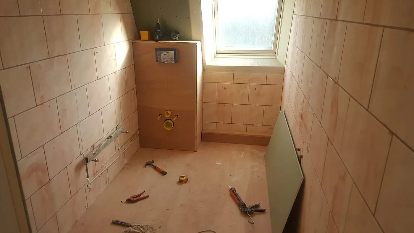 Kale ruimte met inbouwreservoir en onbetegelde wanden vóór de renovatie — badkamerrenovatie in De Hoogte door BontBouw