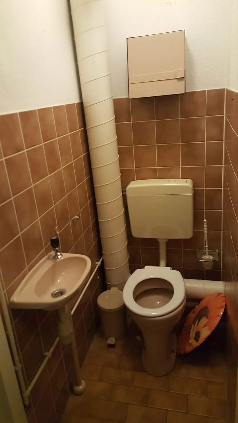 Oud toilet met bruine tegels en staand reservoir vóór de renovatie — toiletrenovatie in Beijum door BontBouw