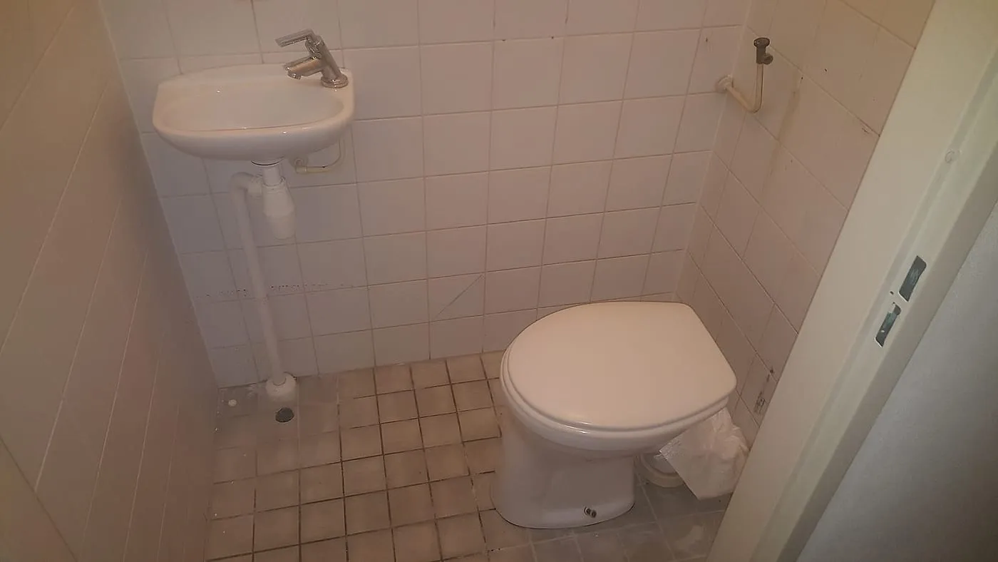 Oud toilet met witte tegeltjes en staande pot vóór de renovatie — toiletrenovatie in De Hunze door BontBouw