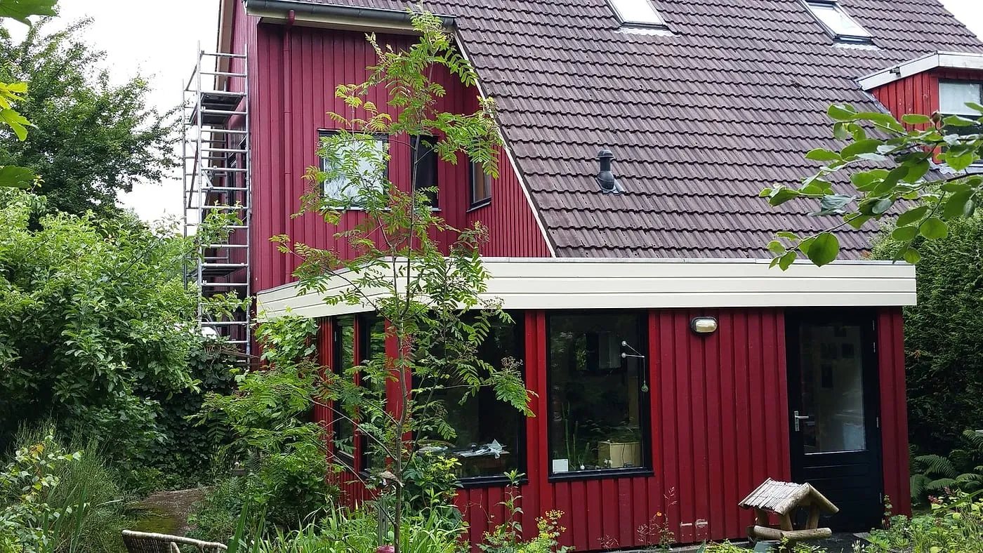 Rode houten gevel met steiger langs de topgevel vóór het werk — schilderwerk in Beijum door BontBouw