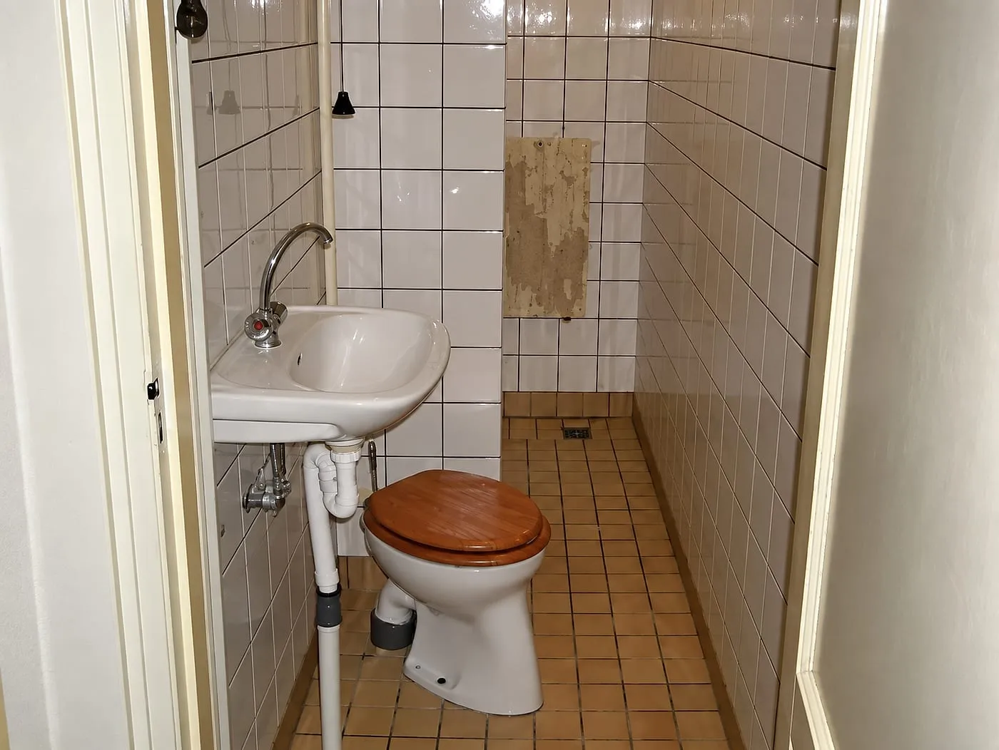 Staand toilet en oud wastafeltje met witte wandtegels vóór de renovatie — badkamerrenovatie in Groningen door BontBouw