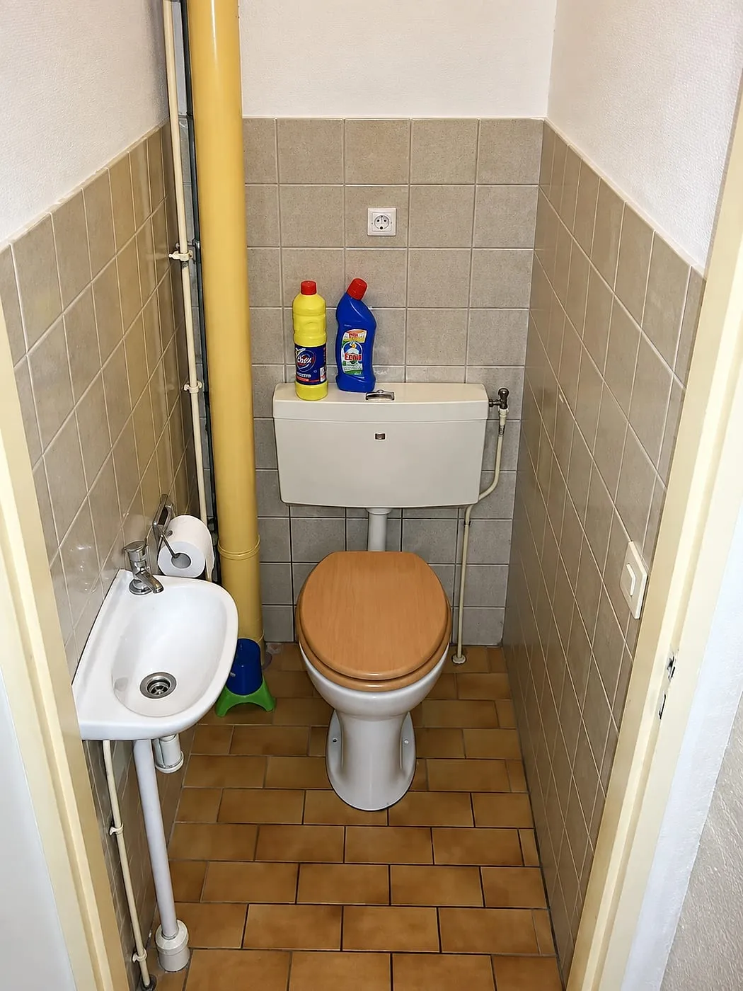 Staande pot met wandreservoir en gele afvoerbuis in de hoek vóór de renovatie — toiletrenovatie in Groningen door BontBouw