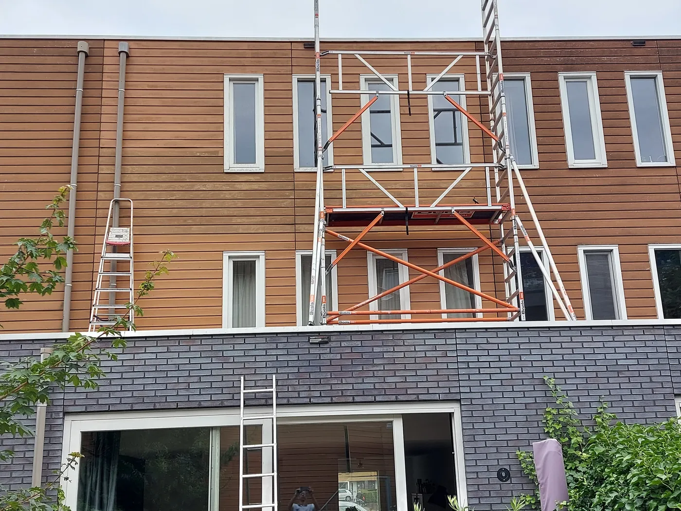 Verweerde houten gevelbekleding met rolsteiger en ladders vóór het werk — schilderwerk in Groningen door BontBouw