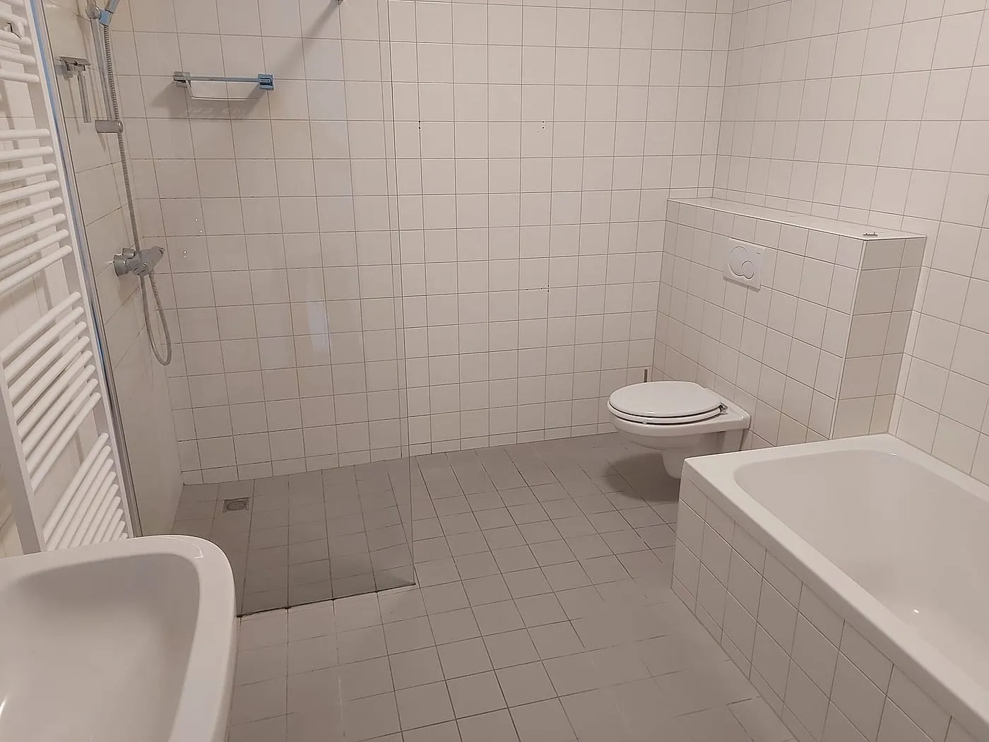 Witte tegeltjes met douchehoek en ligbad vóór de renovatie — badkamerrenovatie in Schildersbuurt door BontBouw
