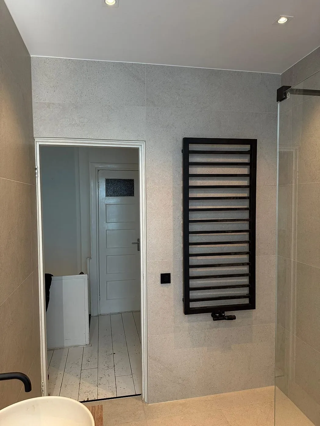 Doorgang met zwarte handdoekradiator na de renovatie — badkamerrenovatie in Korrewegwijk door BontBouw