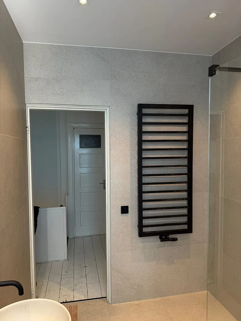 Zwarte handdoekradiator naast de douche — badkamerrenovatie in Korrewegwijk door BontBouw