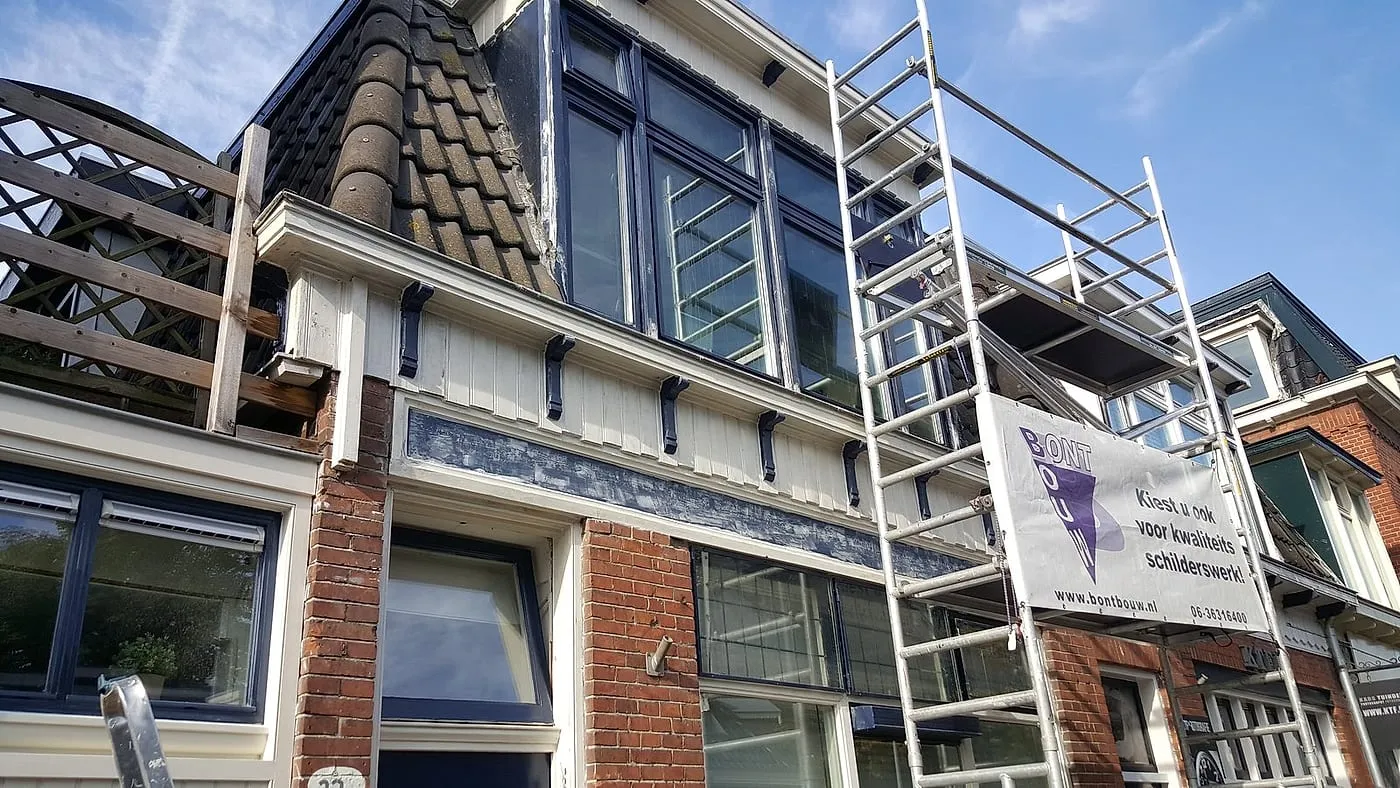Verweerde dakkapel en kroonlijst met rolsteiger tegen de gevel vóór het werk — schilderwerk in Eeldersingel door BontBouw
