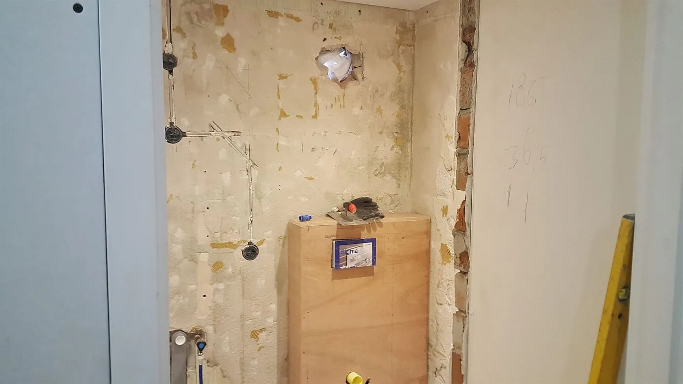 Voorzetwand met inbouwreservoir in de gestripte ruimte vóór de renovatie — badkamerrenovatie in Peize door Bontbouw