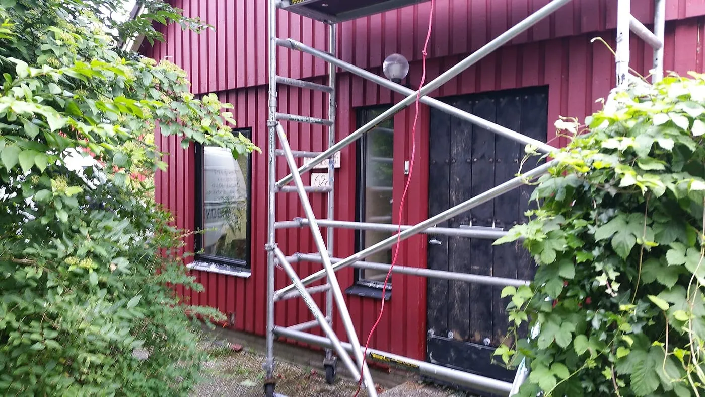 Rolsteiger bij de zwarte voordeur in de rode houtgevel vóór het werk — schilderwerk in Beijum door BontBouw