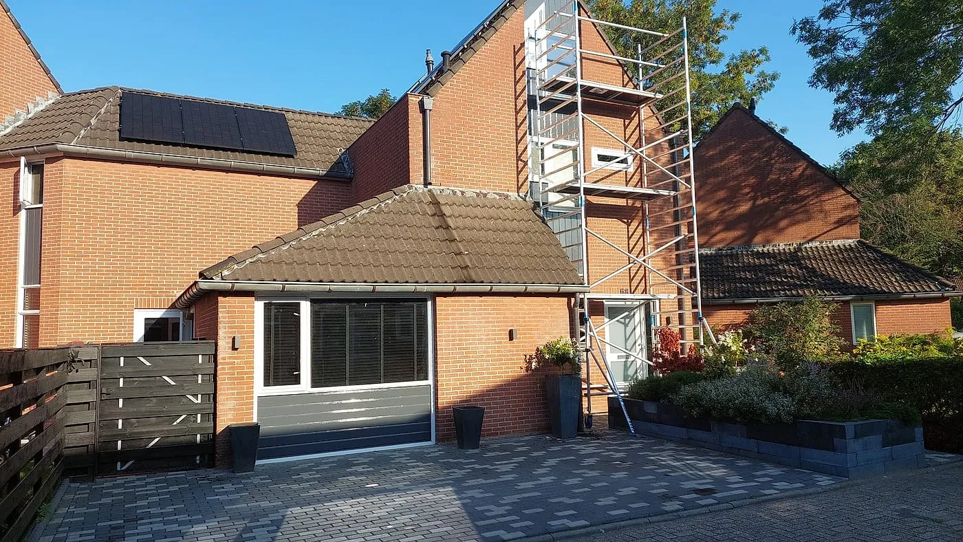 Rode gevel met steiger vóór het werk — schilderwerk in Beijum door BontBouw