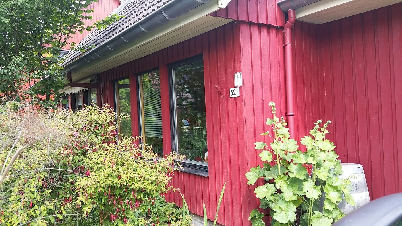 Verweerde rode gevel met zwarte kozijnen langs de border vóór het werk — schilderwerk in Beijum door BontBouw