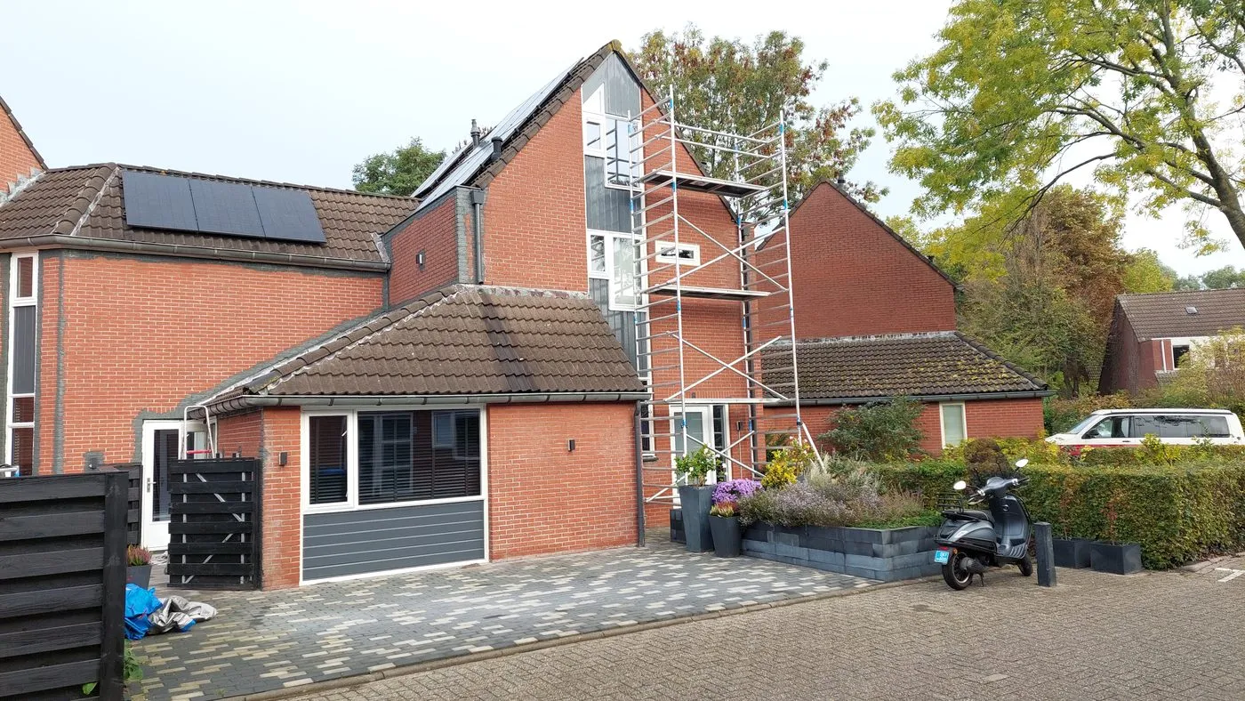 Rode gevel met uitbouw en rolsteiger vóór het werk — schilderwerk in Beijum door BontBouw