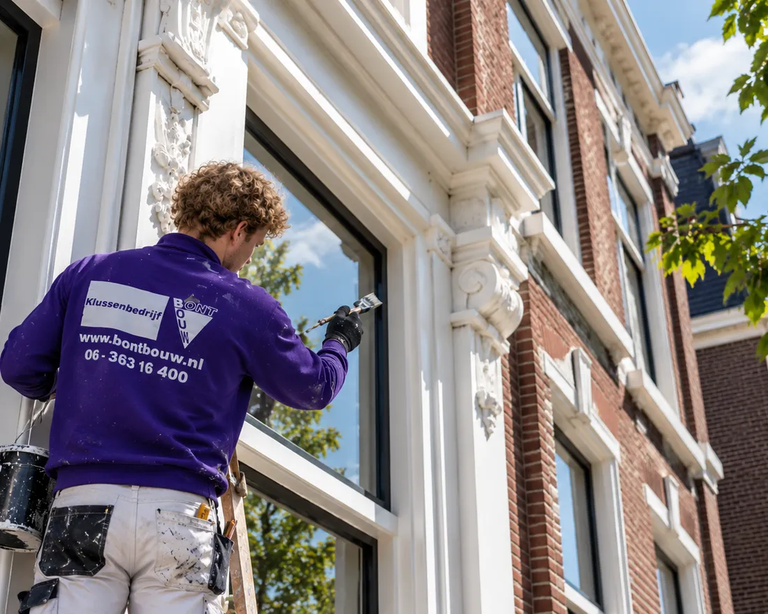 Schilder van BontBouw lakt het kozijn van een herenpand met stucwerk in Groningen