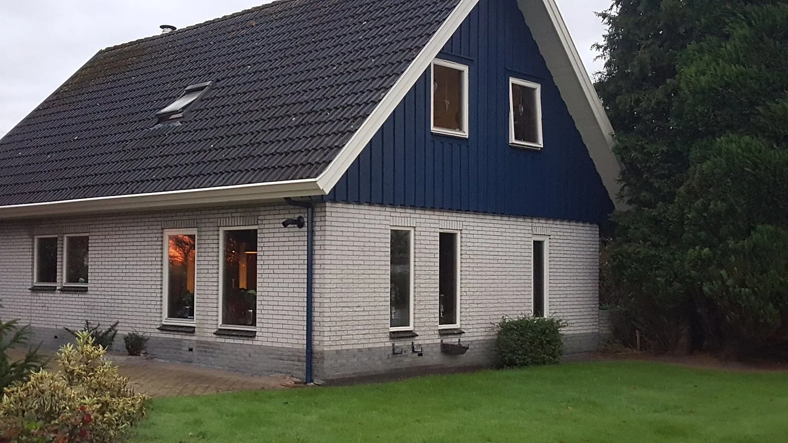 Blauwe topgevel met witte kozijnen na het werk — schilderwerk in Euvelgunne door BontBouw