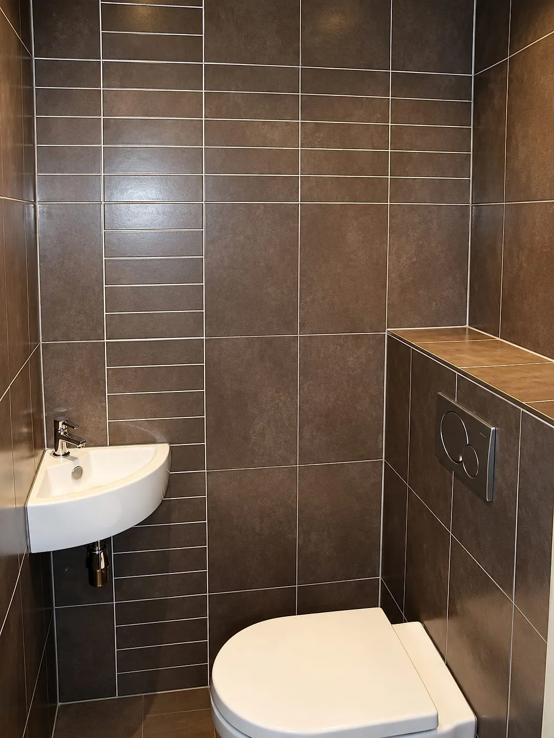 Bruine tegelwand met hoekfontein en halfhoge voorzetwand na de renovatie — toiletrenovatie in Groningen door BontBouw