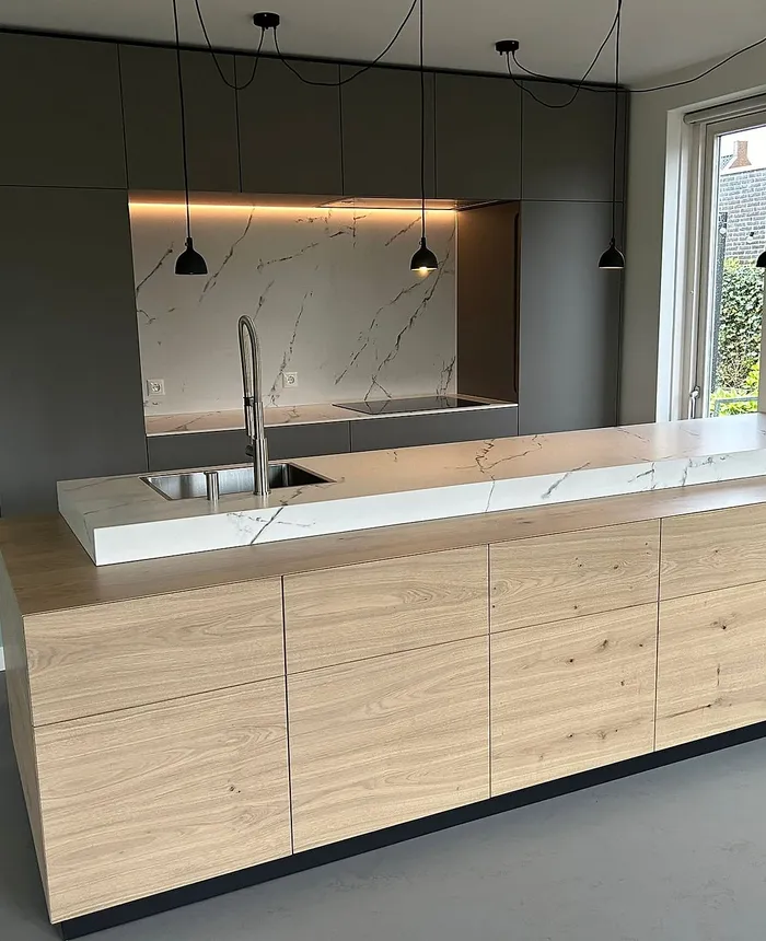 Verbouwde keuken in Groningen met een eiken kookeiland en een donkere kastenwand