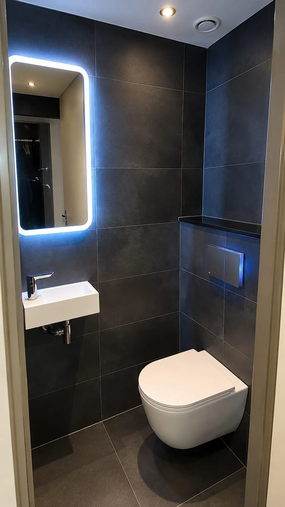 Hangtoilet met antracieten tegels en verlichte spiegel na de renovatie — toiletrenovatie in Beijum door BontBouw