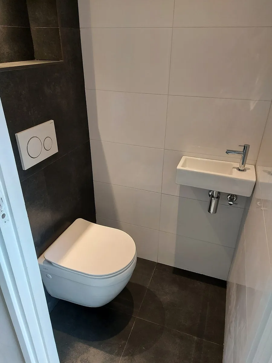 Toilet met antracieten tegelwand in De Hunze — toiletrenovatie door BontBouw
