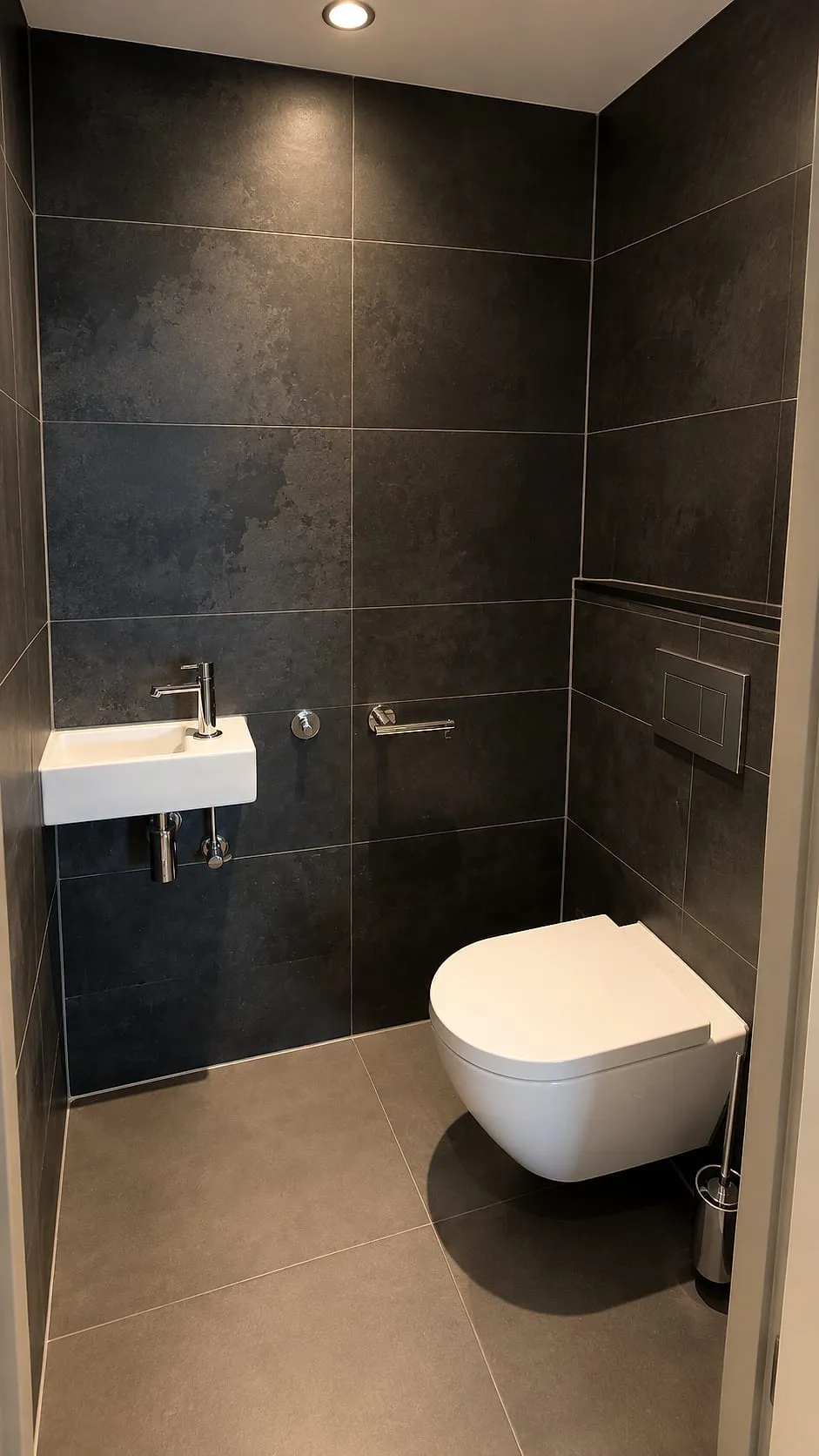 Hangtoilet met antracieten wandtegels en witte fontein na de renovatie — toiletrenovatie in Kropswolde door BontBouw