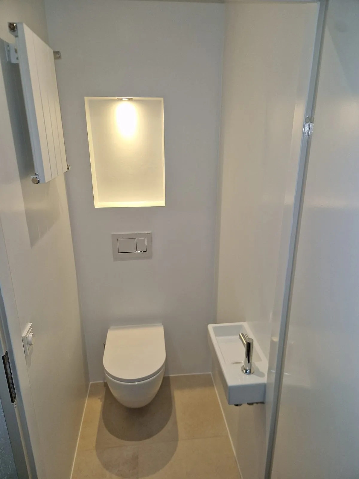 Hangtoilet met verlichte nis en witte designradiator na de renovatie — toiletrenovatie in Ulgersmaborg door BontBouw