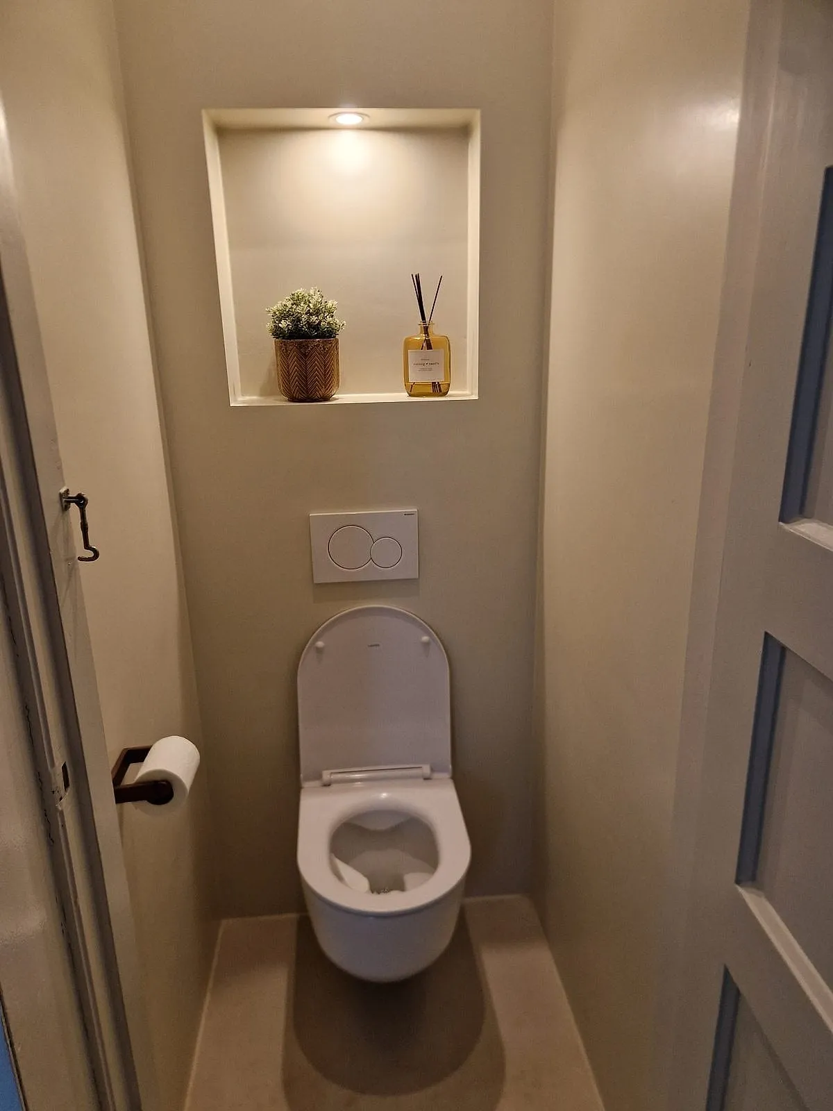 Hangtoilet met verlichte nis in gestucte wanden na de renovatie — toiletrenovatie in Korrewegwijk door BontBouw