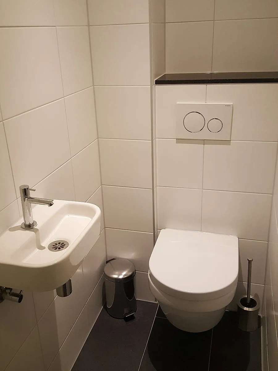 Wc met witte tegels en donkere vloer in Beijum — toiletrenovatie door BontBouw