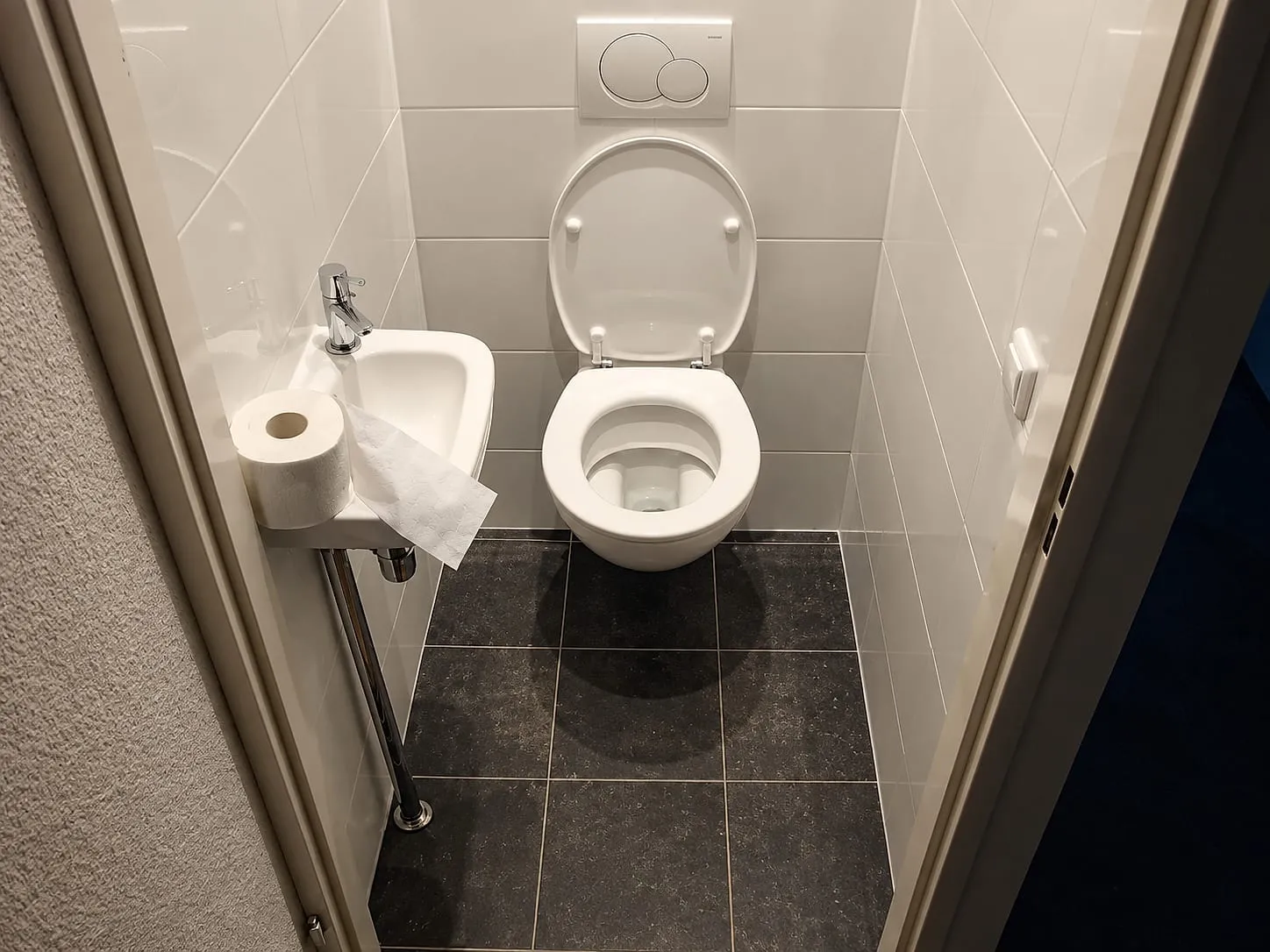 Hangtoilet met witte wandtegels tot plafond en donkergrijze vloer na de renovatie — toiletrenovatie in Groningen door BontBouw