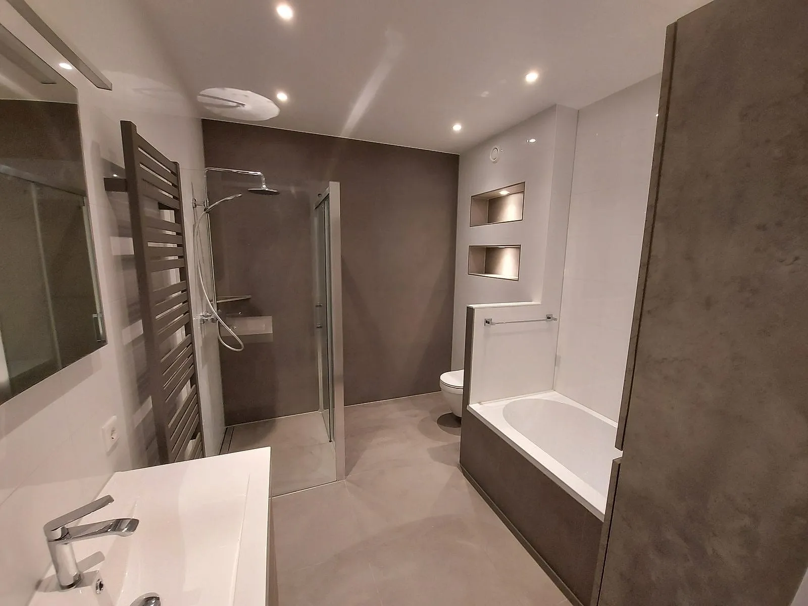 Inloopdouche en ligbad met verlichte nissen na de renovatie — badkamerrenovatie in Schildersbuurt door BontBouw