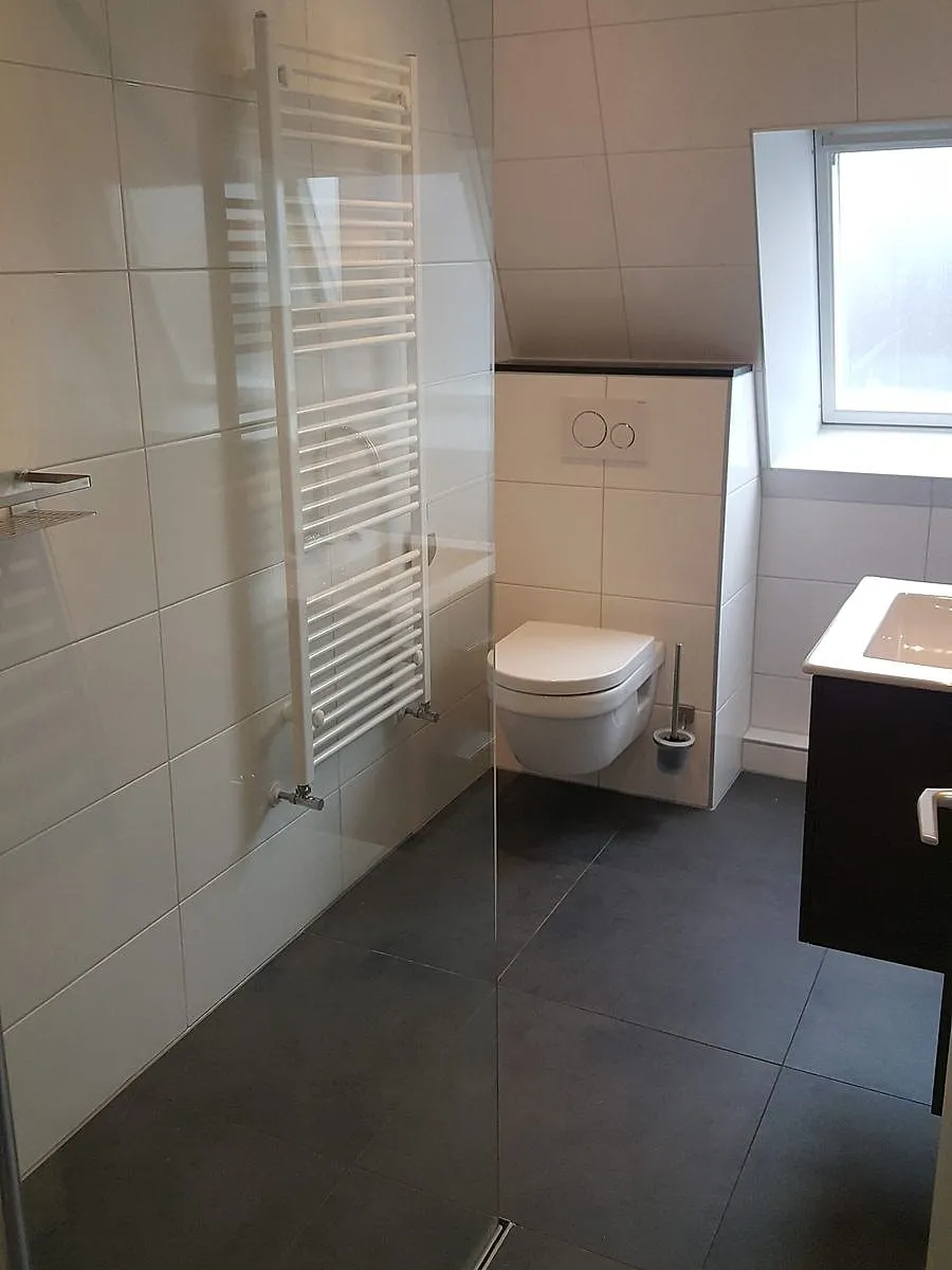 Badkamer met schuine tegelwand in De Hoogte — badkamerrenovatie door BontBouw