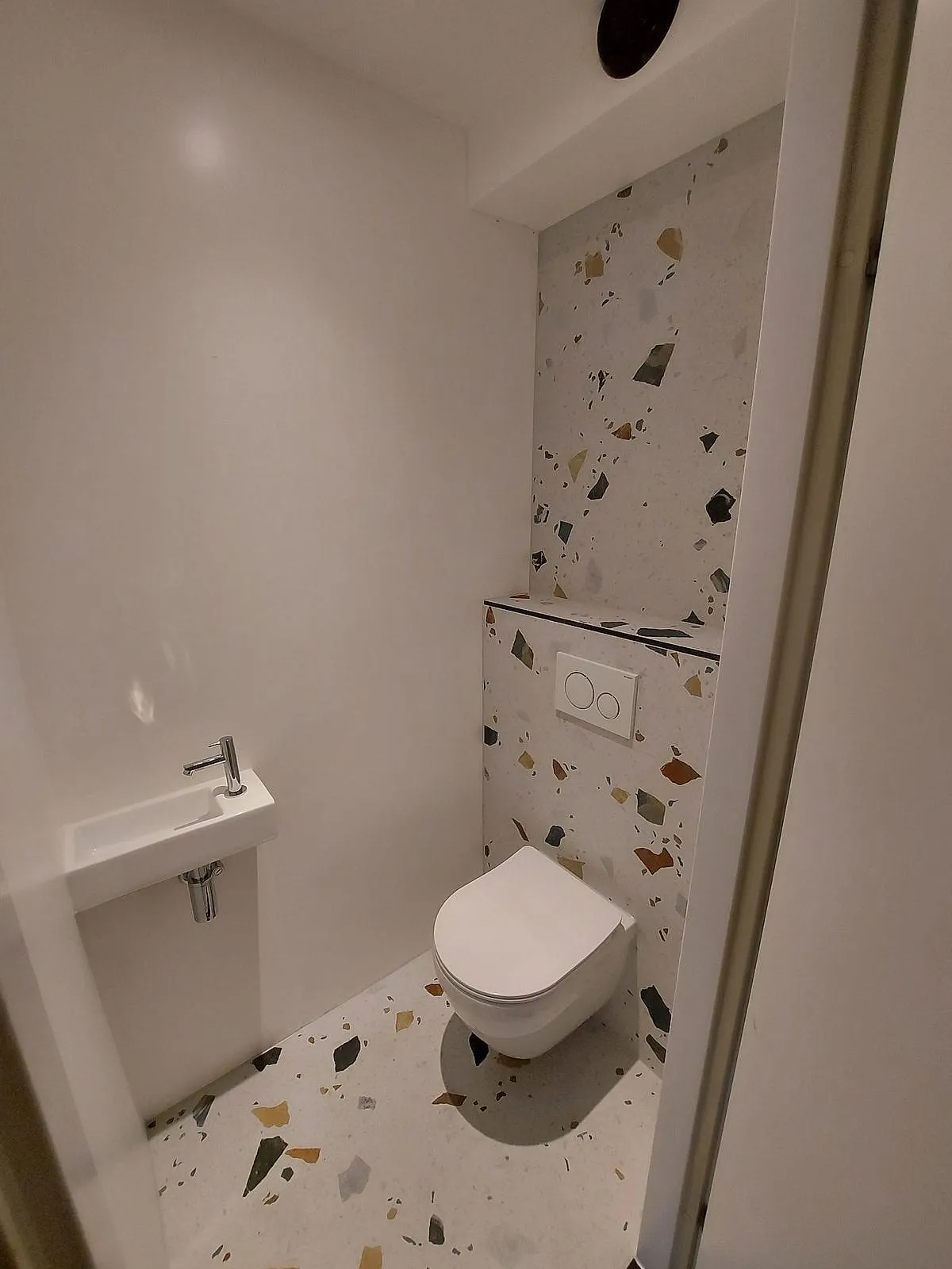 Toilet met terrazzo wand en vloer na de renovatie — toiletrenovatie in Schildersbuurt door BontBouw