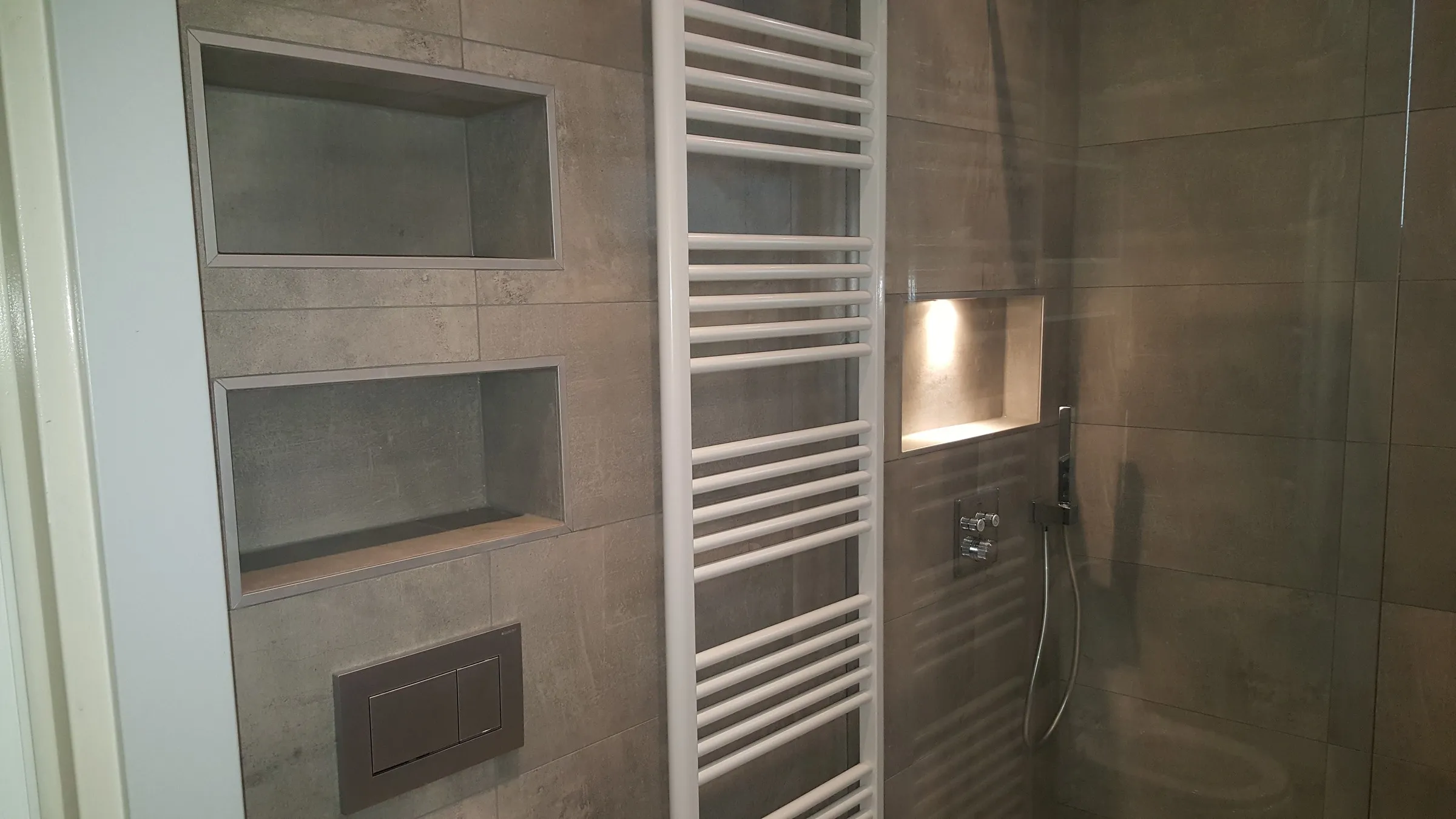 Twee nissen boven het hangtoilet naast de inloopdouche in betonlook na de renovatie — badkamerrenovatie in De Hunze door BontBouw
