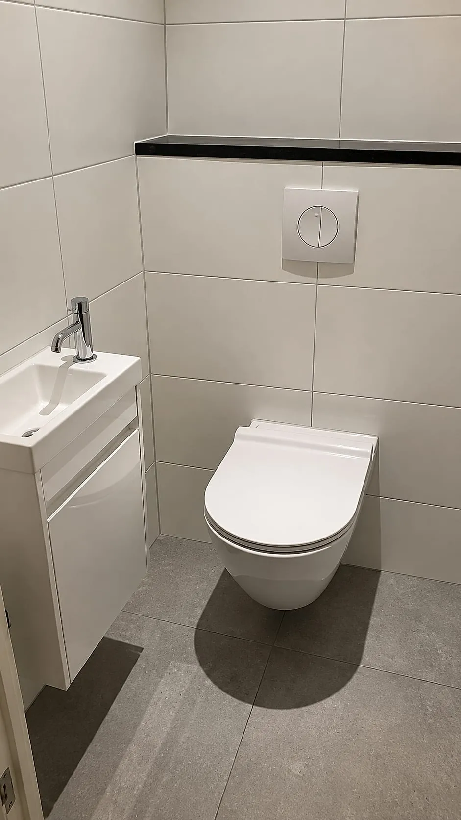 Wit hangtoilet en fonteinkast onder hardstenen richel na de renovatie — toiletrenovatie in Groningen door BontBouw