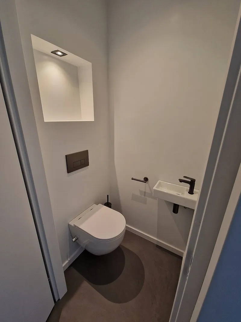 Wit toilet met naadloze gietvloer in Roden — toiletrenovatie door Bontbouw