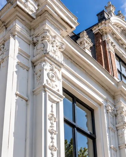 Wit geschilderd lijstwerk en ornamenten aan de gevel van een monumentaal pand in Groningen