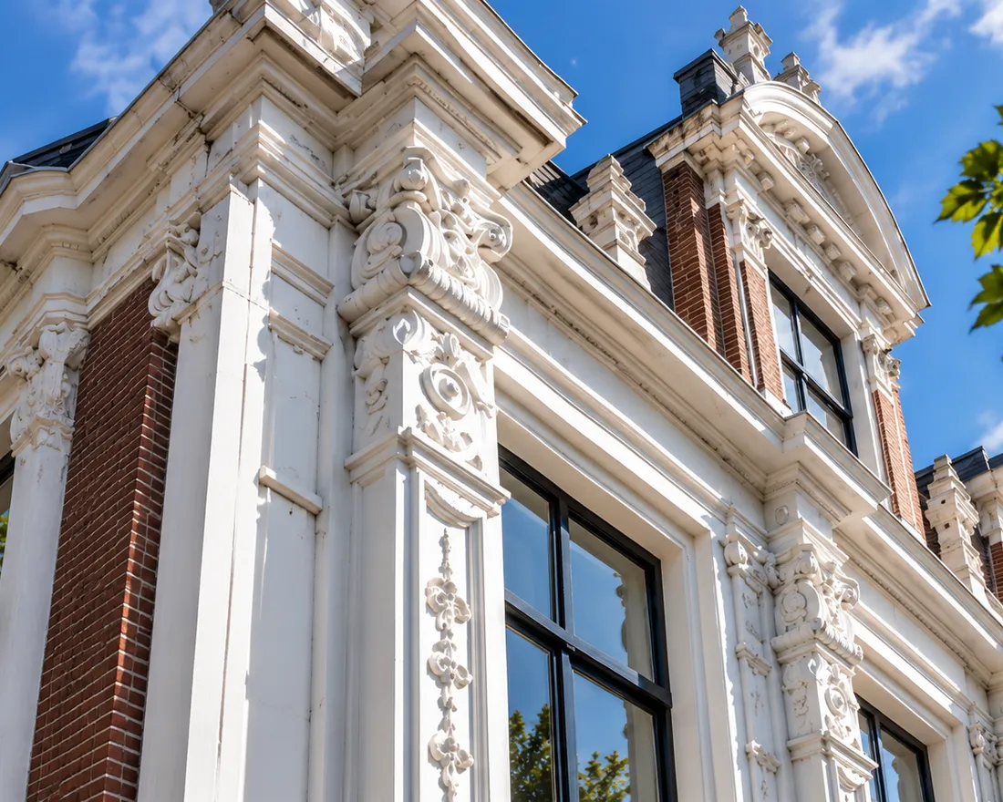Wit geschilderd lijstwerk en ornamenten aan de gevel van een monumentaal pand in Groningen
