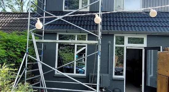 Steiger tegen een donkergrijze houten gevel tijdens het schilderwerk